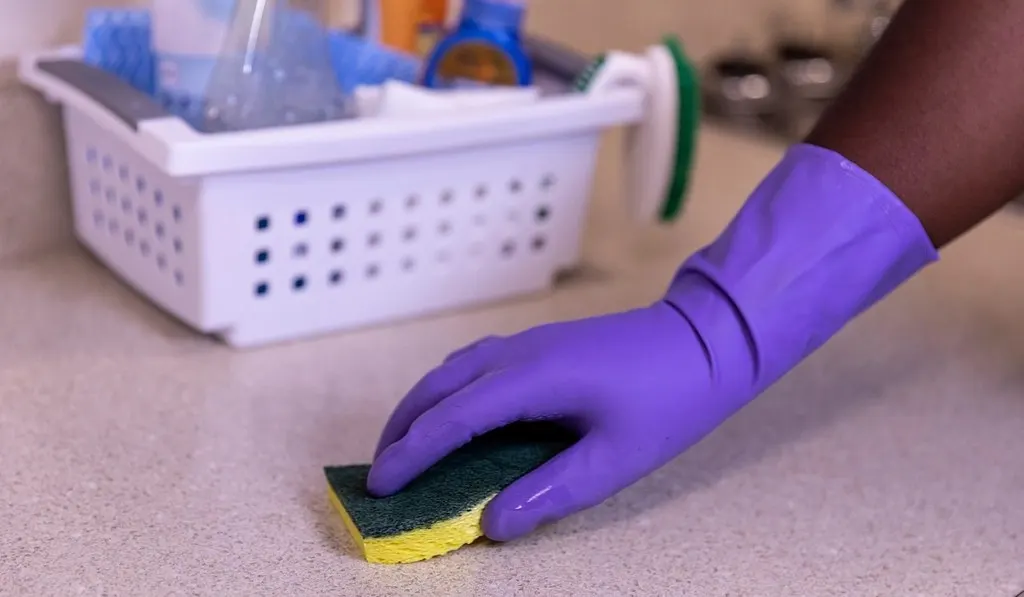 Aanrecht wordt schoongemaakt met een spons en een handschoen